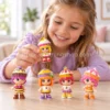 Niña jugando sobre una mesa con cinco muñecas Pinypon Cupcakes con peinados de pastelitos de colores.