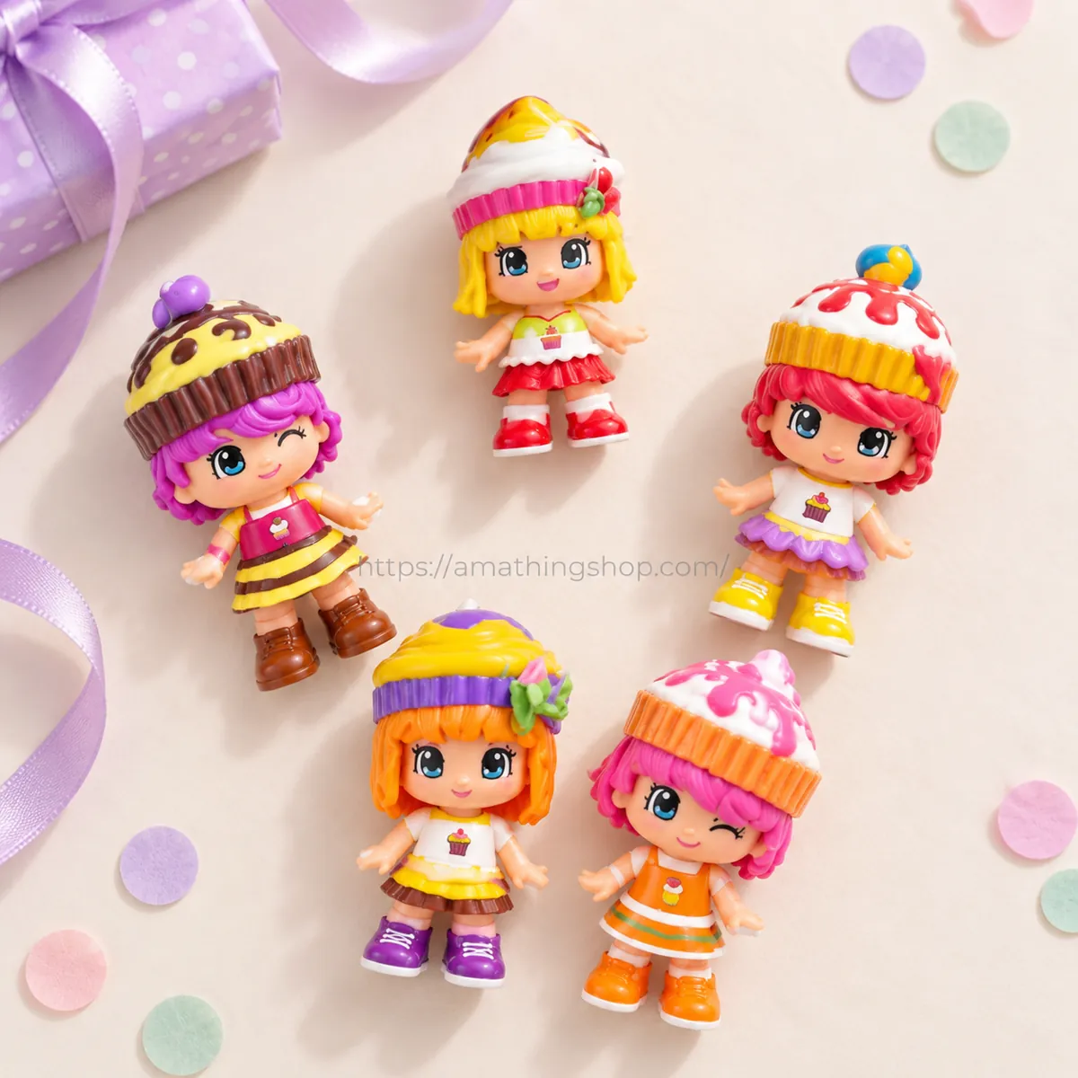 Cinco muñecas Pinypon Cupcakes con peinados de pastelitos sobre fondo claro, junto a un regalo envuelto y una cinta lila.
