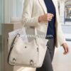 Modelo elegante llevando al hombro el bolso grande Desigual Minuet Rotterdam beige con diseño bordado. Bolso tote estructurado ideal para llevar portátil y documentos A4 al trabajo o universidad. Disponible en amathingshop.com.