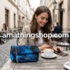 Mujer joven en una terraza de cafetería usando un bolso pequeño Desigual Camoflower Zurich azul floral acolchado, mostrando su tamaño compacto junto a un café.