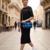 Primer plano de mujer moderna caminando por ciudad europea llevando el bolso pequeño Desigual Camoflower Zurich azul con estampado floral acolchado en bandolera, estilo casual chic.