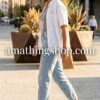 Mujer joven sonriente caminando con look casual de vaqueros y zapatillas Adidas Grand Court negras con bandas plateadas, estilo urbano de amathingshop.com.