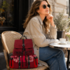 Mochila Desigual mujer roja Clementine Tribeca en café urbano Mochila Desigual Back Rich Clementine Tribeca roja para mujer colocada sobre una silla de café, con diseño urbano, detalles florales, correas negras y tamaño aproximado visible en escena lifestyle.