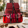 Mochila Desigual mujer roja con bolsillos Back Rich Clementine Tribeca Mochila Desigual Back Rich Clementine Tribeca roja para mujer sobre mesa de café, con bolsillos exteriores, cierre tipo cartera, cordón ajustable y detalles florales.