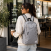 Mujer de 30 años utilizando la mochila Jordan Gris Air Jordan original de 21 litros con compartimento para portátil mientras sale de una cafetería con estilo urbano.