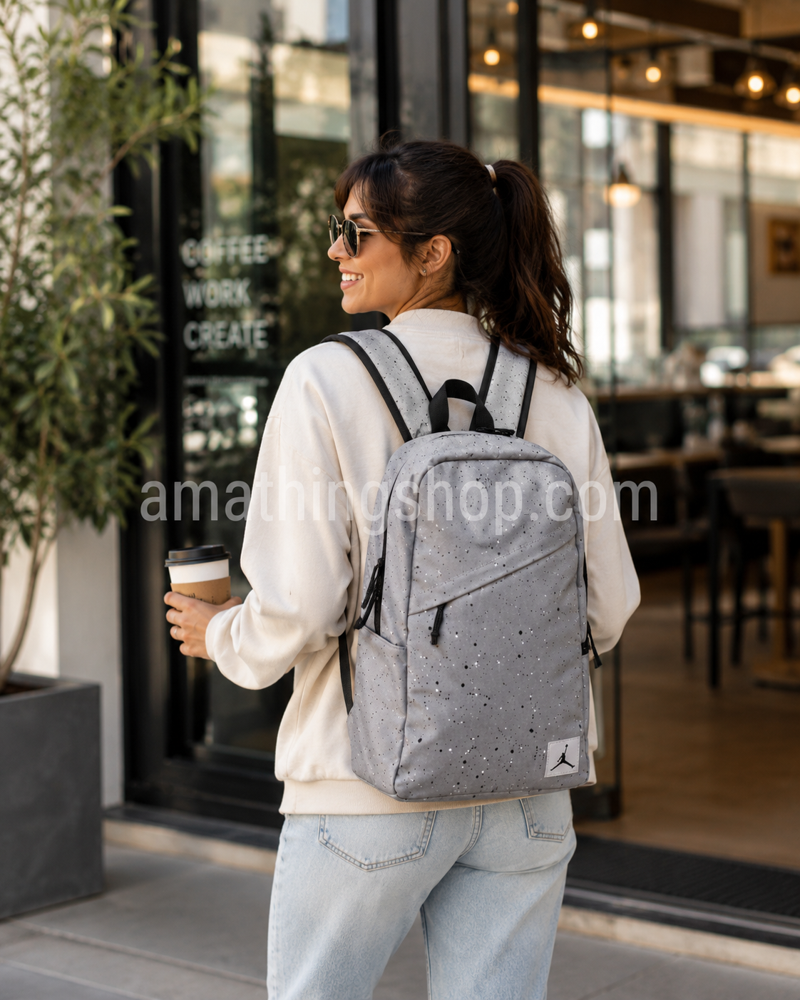 Mujer de 30 años utilizando la mochila Jordan Gris Air Jordan original de 21 litros con compartimento para portátil mientras sale de una cafetería con estilo urbano.