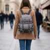Mochila Desigual mujer gris con bordado LOVE usada en la espalda en un entorno urbano, ideal para uso diario, trabajo o paseos por la ciudad.