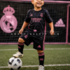 Niño de 3 años usando conjunto Real Madrid Adidas negro y rosa completo con camiseta, pantalón y medias.