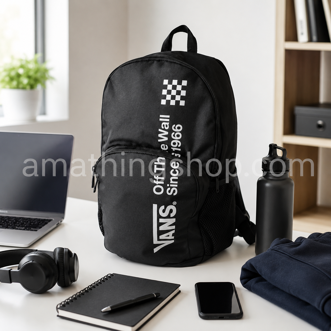 Mochila Vans Alumni Pack 3 B negra 27L sobre escritorio con portátil, libreta, auriculares, móvil, botella y sudadera, ideal para universidad, trabajo, gimnasio, viajes cortos y uso diario.