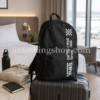 Mochila Vans Alumni Pack 3 B negra 27L sobre maleta en habitación de hotel, ideal para viaje corto, escapada de fin de semana, equipaje de mano, universidad, trabajo y uso diario.