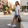Mujer joven con estilo urbano vistiendo falda vaquera y camisa blanca con zapatillas Adidas Superstar de punta plateada, look de día en la ciudad, disponible en amathingshop.com.