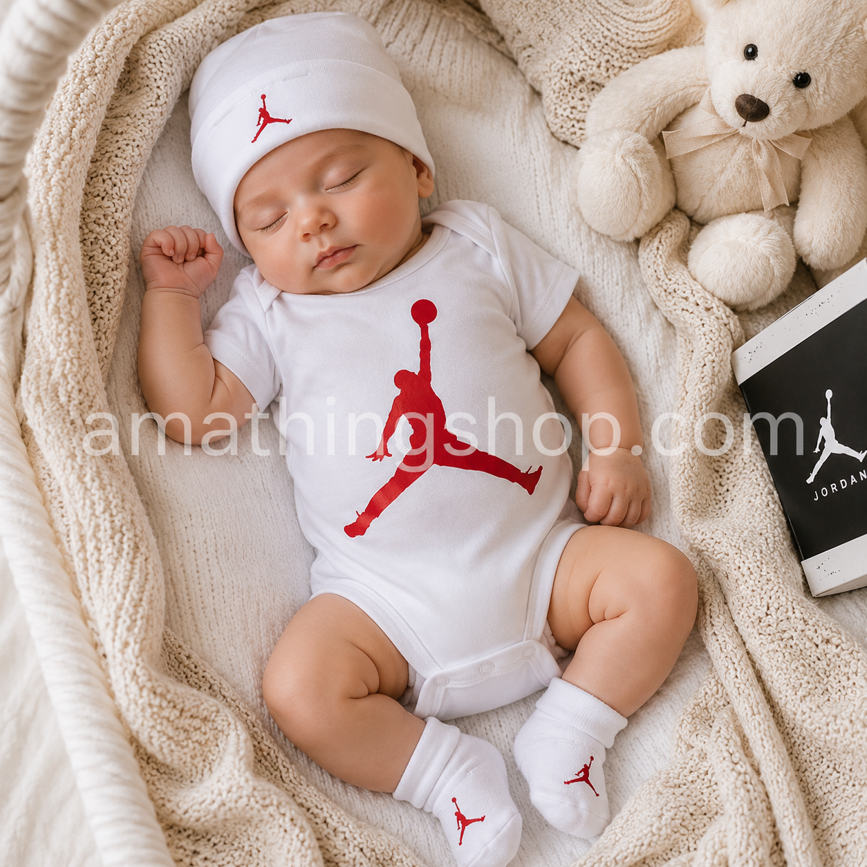 Bebé recién nacido durmiendo con conjunto Nike Air Jordan de 3 piezas blanco y rojo compuesto por body, gorro y patucos modelo MJ0041-001 en un capazo de punto