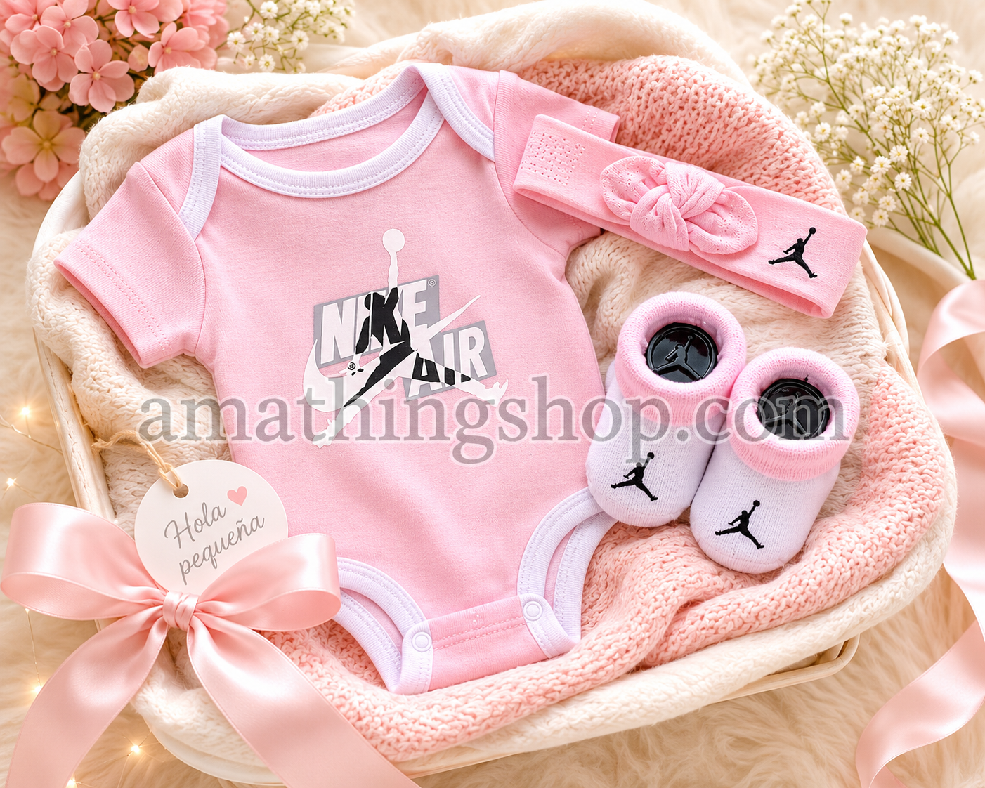 Canastilla para recién nacida con conjunto Jordan rosa formado por body, diadema y patucos sobre manta suave.