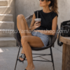 Mujer de 35 años usando chanclas Adidas Adissage negras con bandas blancas y plantilla de masaje en una terraza exterior.