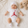 Bebé sonriendo con conjunto Nike Air Jordan de 3 piezas blanco y rojo compuesto por body, gorro y patucos modelo MJ0041-001 para 0-6 meses