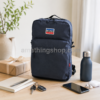 Mochila Levi’s Mini L Pack azul marino 13L sobre mesa con libreta, llaves, móvil, auriculares, botella y paquete de regalo, ideal como mochila compacta unisex para uso diario, trabajo, universidad y escapadas ligeras.