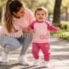 Bebé niña caminando junto a su madre con chándal Adidas rosa de sudadera y pantalón en un paseo al aire libre.