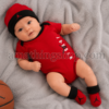 Bebé recién nacido con conjunto Jordan rojo compuesto por body, gorro y patucos sobre manta gris suave.
