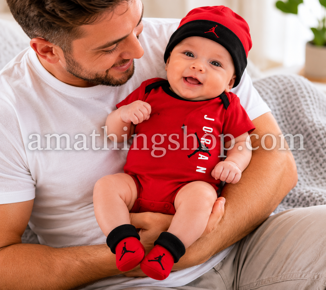 Bebé sonriente con conjunto Jordan rojo compuesto por body, gorro y patucos sobre ambiente cálido familiar.