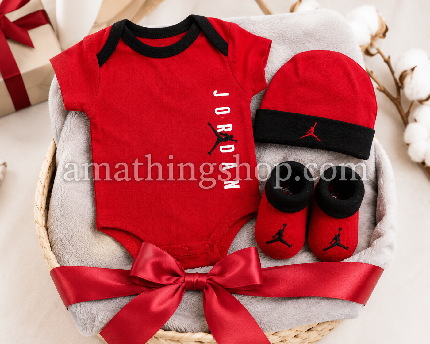 Canastilla para recién nacido con conjunto Jordan rojo compuesto por body, gorro y patucos sobre manta suave.