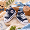Converse First Star bebé azul como regalo de nacimiento Zapatillas Converse First Star azul marino para bebé presentadas como regalo de nacimiento sobre manta suave con lazo azul.