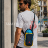 Hombre usando bandolera Nike Jordan portabotellas azul y amarillo mientras pasea por ciudad en ambiente urbano lifestyle.