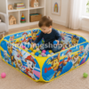 Niño pequeño jugando dentro de una piscina de bolas Paw Patrol en el salón de casa con pelotas de colores.