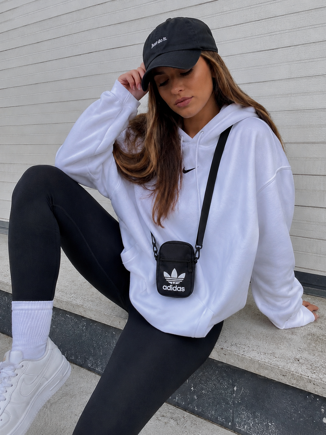 Mujer joven con bolso bandolera Adidas Originals Fest Bag EI7411 negro unisex pequeño cruzado para uso diario, viajes y estilo streetwear.