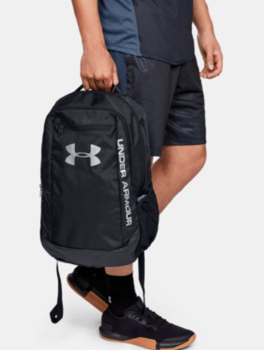 Persona llevando la mochila Under armour hustle negra en un entorno urbano