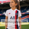Niña con camiseta oficial PSG Nike blanca temporada 2019 2020 en estadio de fútbol con diseño deportivo infantil.