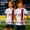 Niño y niña con camiseta oficial PSG Nike blanca 2019 2020 en estadio de fútbol con diseño deportivo infantil.