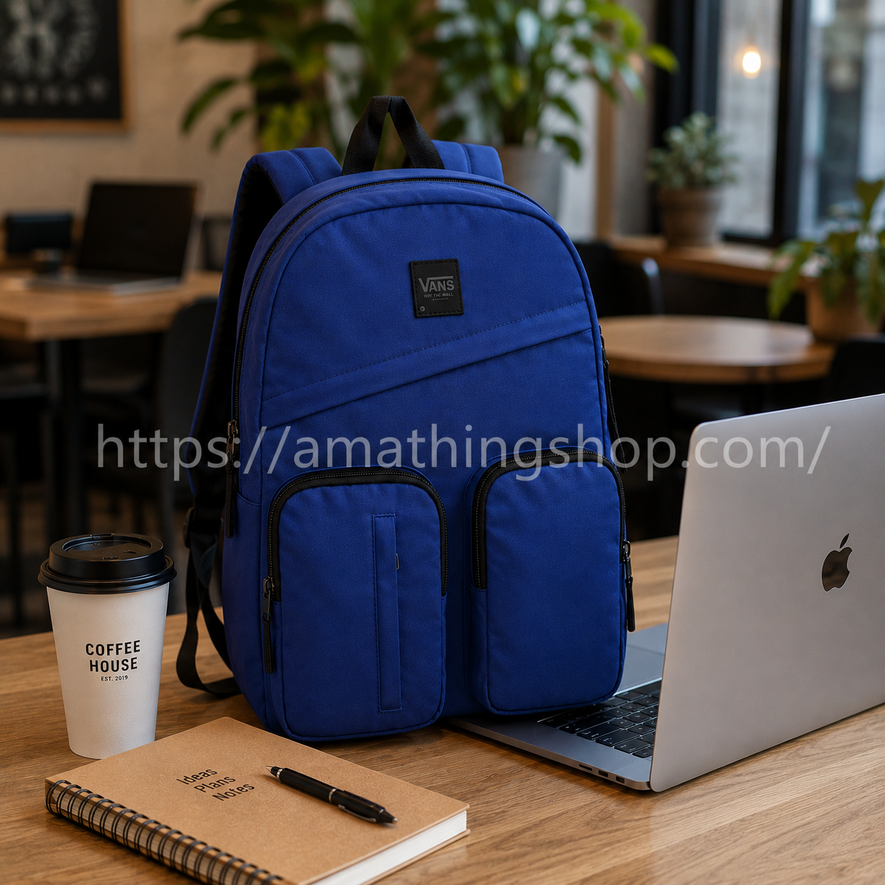 Mochila ligera Vans azul marino junto a portátil en cafetería moderna premium