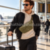 Hombre viajando con riñonera Jordan Air Crossbody verde oliva y maleta de cabina en aeropuerto