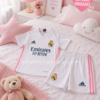 Conjunto Real Madrid niña Adidas blanco rosa sobre cama infantil decorada en tonos pastel