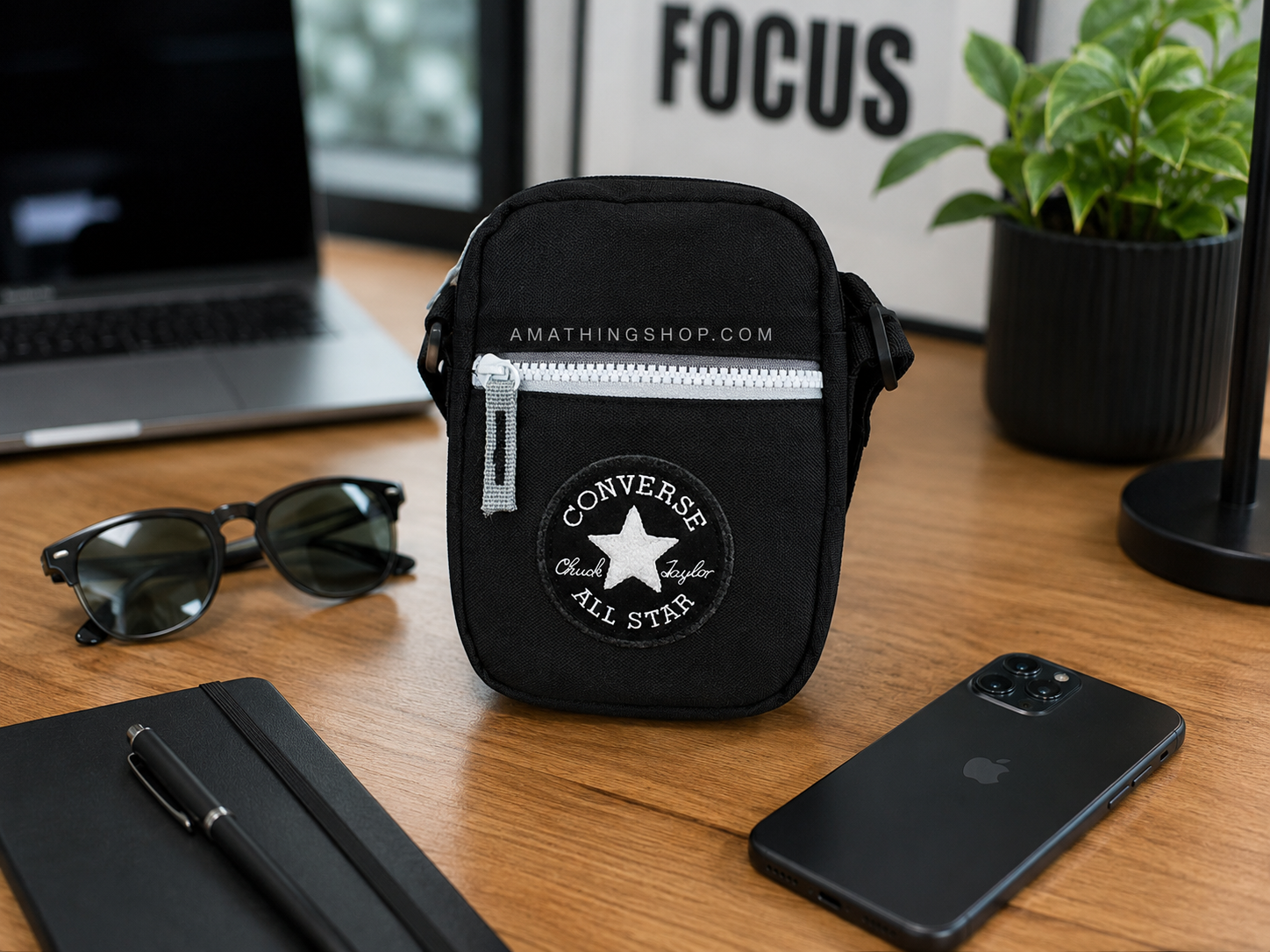Bandolera Converse negra sobre escritorio lifestyle urbano Bandolera Converse negra tipo crossbody sobre mesa moderna con portátil, gafas e iPhone.