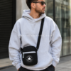 Hombre con bandolera Converse negra estilo streetwear urbano Hombre joven usando bolso bandolera Converse negro tipo crossbody con estilo streetwear urbano.