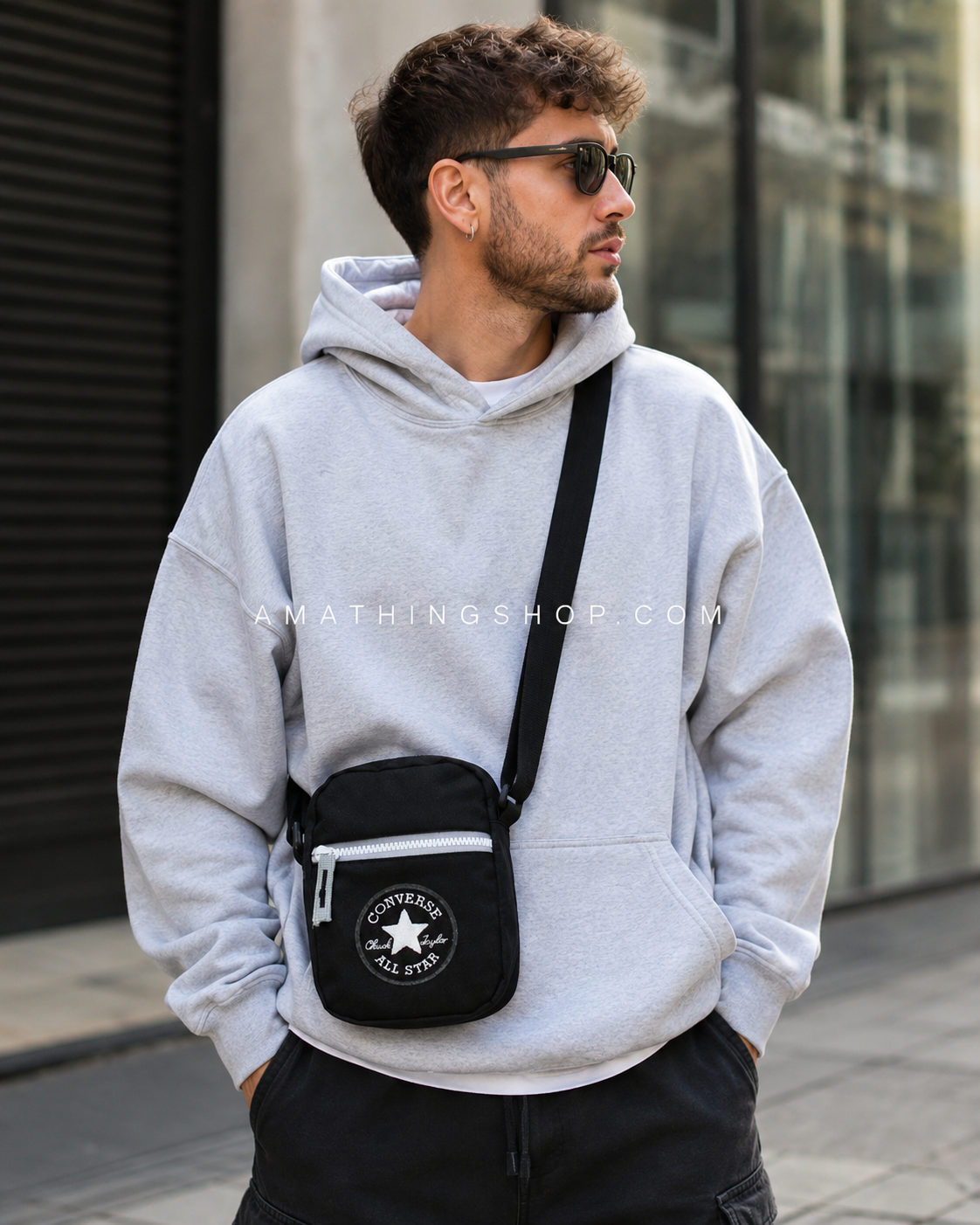 Hombre con bandolera Converse negra estilo streetwear urbano Hombre joven usando bolso bandolera Converse negro tipo crossbody con estilo streetwear urbano.