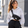 Chica joven con sudadera gris y riñonera Jordan Jumpman negra 9A0623-023 cruzada al pecho, con logotipo blanco y correa ajustable. Copiar ALT