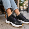 Zapatillas Reebok Royal Pervader para mujer negras con detalles rosa y azul modelo EH2488 en una mujer sentada en una cafetería urbana con look casual