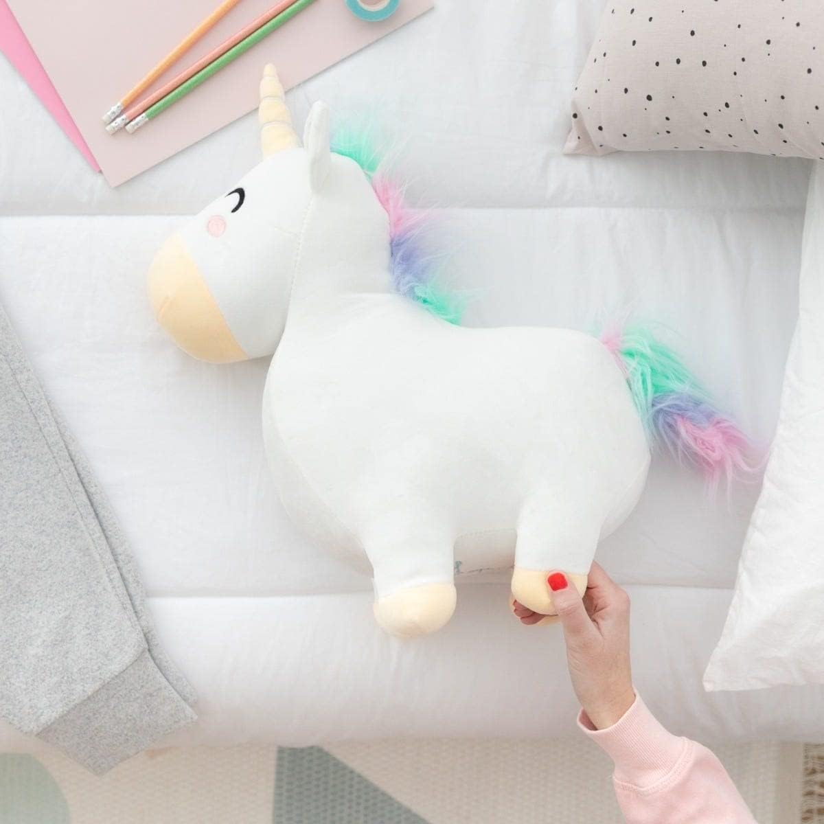 Mr wonderful einhorn kissen kuscheltier sostenido por una mujer de diario.