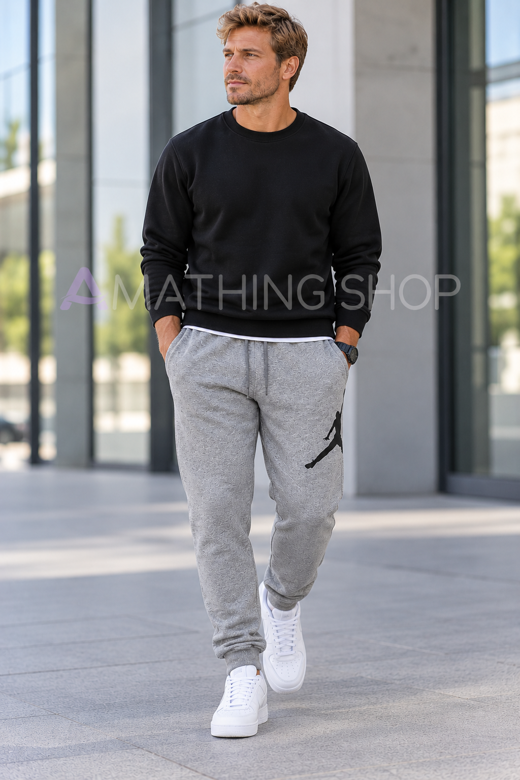 Hombre rubio de unos 40 años con pantalón Jordan Jumpman gris XL, logo negro, sudadera negra y zapatillas blancas en un entorno urbano. Copiar ALT