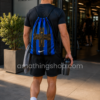 Deportista entrando a un gimnasio con mochila saco Nike Inter de Milán azul y negra, diseño ligero y fino con cordones ajustables para entrenamiento y uso diario.