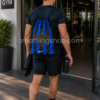 Deportista entrando a gimnasio con mochila saco Nike Inter de Milán azul y negra, diseño oficial ligero con cordones ajustables y capacidad aproximada de 13 litros.