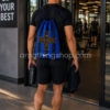 Deportista entrando a gimnasio con mochila saco Nike Inter de Milán azul y negra, diseño oficial ligero y fino con capacidad aproximada de 13 litros para entrenamiento y deporte diario.