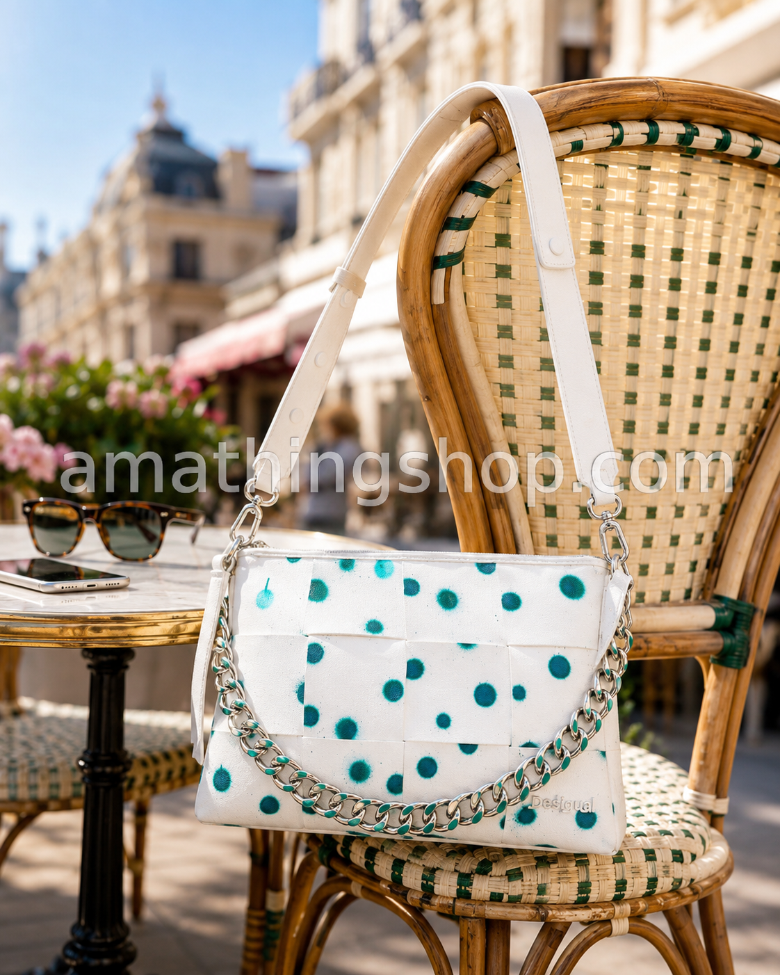 Bolso Desigual New Splatter Dortmund Maxi blanco 24SAXP10-1000 sobre silla de terraza con cadena metálica, correa ajustable y estampado verde turquesa.