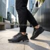 Zapatillas Adidas Ozweego Celox Core Black para hombre (modelo GZ7277) en un entorno urbano moderno. Vista de perfil destacando la silueta técnica, la mediasuela de EVA con amortiguación Adiprene+ y el ajuste ceñido. Calzado de tendencia streetwear disponible en amathingshop.com.