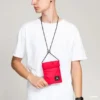 Hombre utilizando mini bandolera Jordan Air Tri Fold roja para móvil, documentación y tarjetas