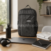 Mochila Adidas Originals RYV negra 29L sobre escritorio con portátil, botella, auriculares, móvil y ropa deportiva, ideal para trabajo, universidad, gimnasio, viajes cortos y uso diario.