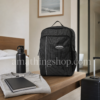Mochila Adidas Originals RYV negra 29L sobre mesa en habitación de hotel con libreta, sudadera, botella y maleta, ideal para viaje corto, escapadas de fin de semana y uso diario.