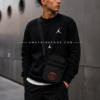 Hombre usando bandolera Jordan PSG negra estilo urbano moderno en escenario europeo minimalista.